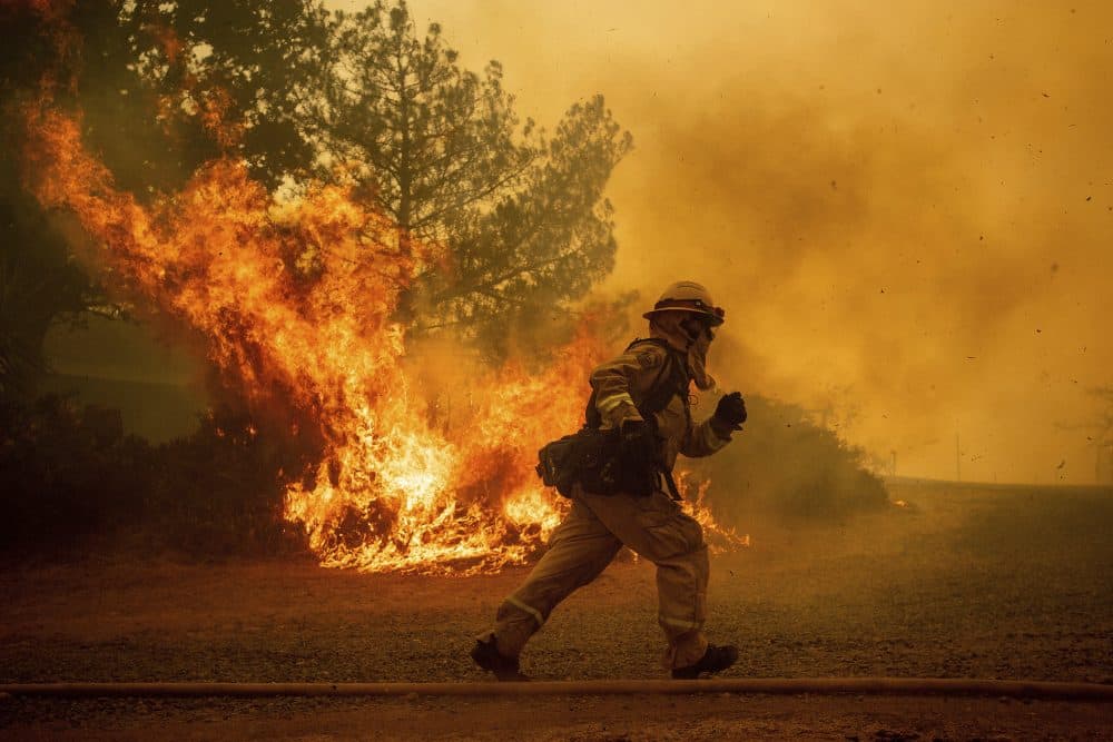 A firefighter runs while trying to save a home as a wildfire tears through Lakeport, Calif., Tuesday, July 31, 2018. (Noah Berger/AP)