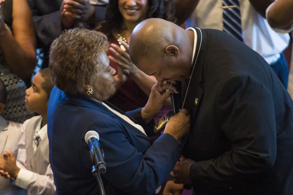 Gross bows his head to receive his new Boston police commissioner badge from his mother Deanna. (Jesse Costa/WBUR)