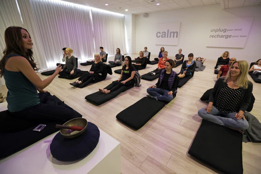 In this Feb. 21, 2016 photo, Lauren Eckstrom, left, begins a session at Unplug Meditation Center in Los Angeles. As a distracted, multi-tasking lifestyle has given way to a more self-aware, live in the moment attitude, meditation practices and mindfulness exercises have moved from hippie to mainstream. Drop-in meditation studios are proliferating in big cities like New York and Los Angeles. (Nick Ut/AP)