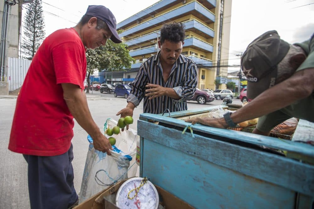 A customer buys limes from a produce cart on Av Ramón Ernesto Cruz in Tegucigalpa. (Jesse Costa/WBUR)
