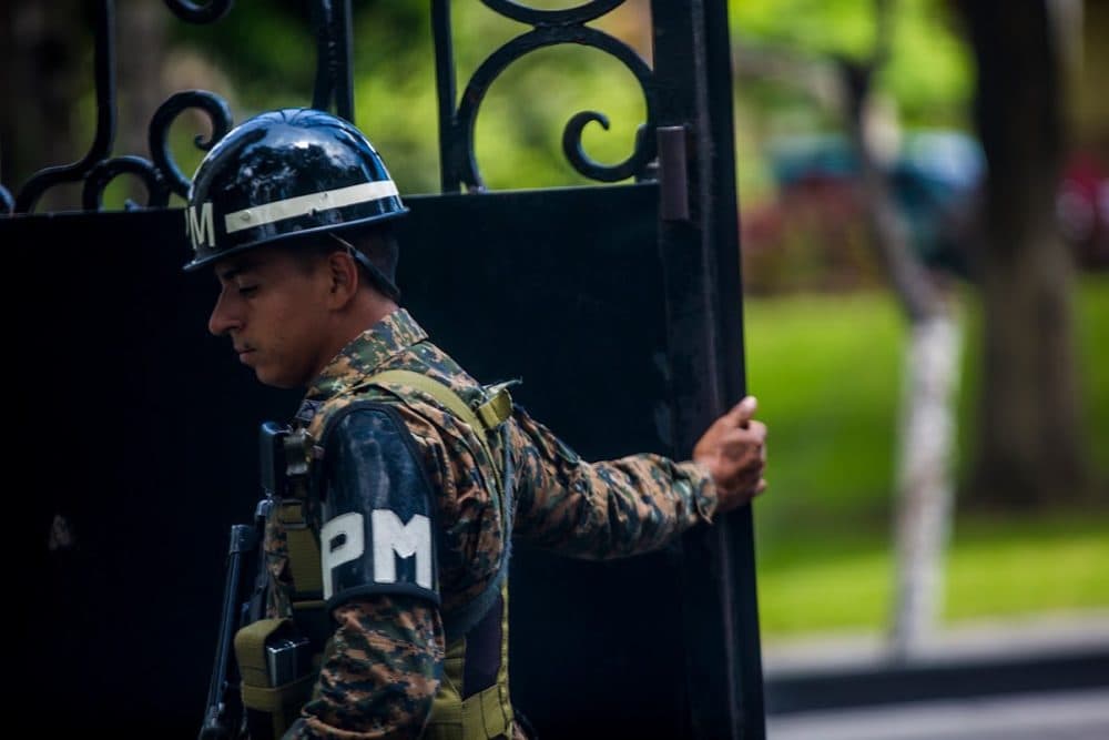 An El Salvadoran Military Police officer opens the gate at the Casa Presidencial or "Presidential House." (Jesse Costa/WBUR)