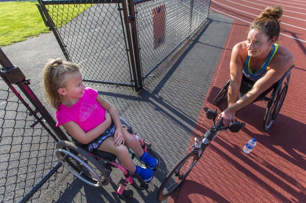 Nine-year-old Maddie Wilson, left, and Tatyana McFadden chat after their workouts at Wellesley High School. (Jesse Costa/WBUR)