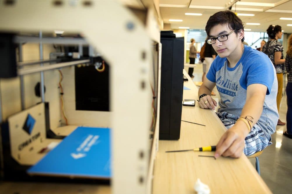 Dearborn STEM Academy student Elias Arroyave checks the functioning of a 3D printer in the school's Fab Lab maker space. (Robin Lubbock/WBUR)