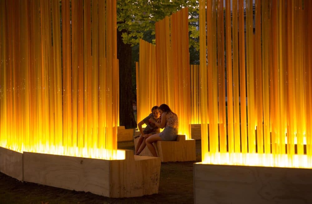 As night falls, visitors sit in the illuminated circles of Fernández's &quot;Autumn (…Nothing Personal).&quot; (Robin Lubbock/WBUR)