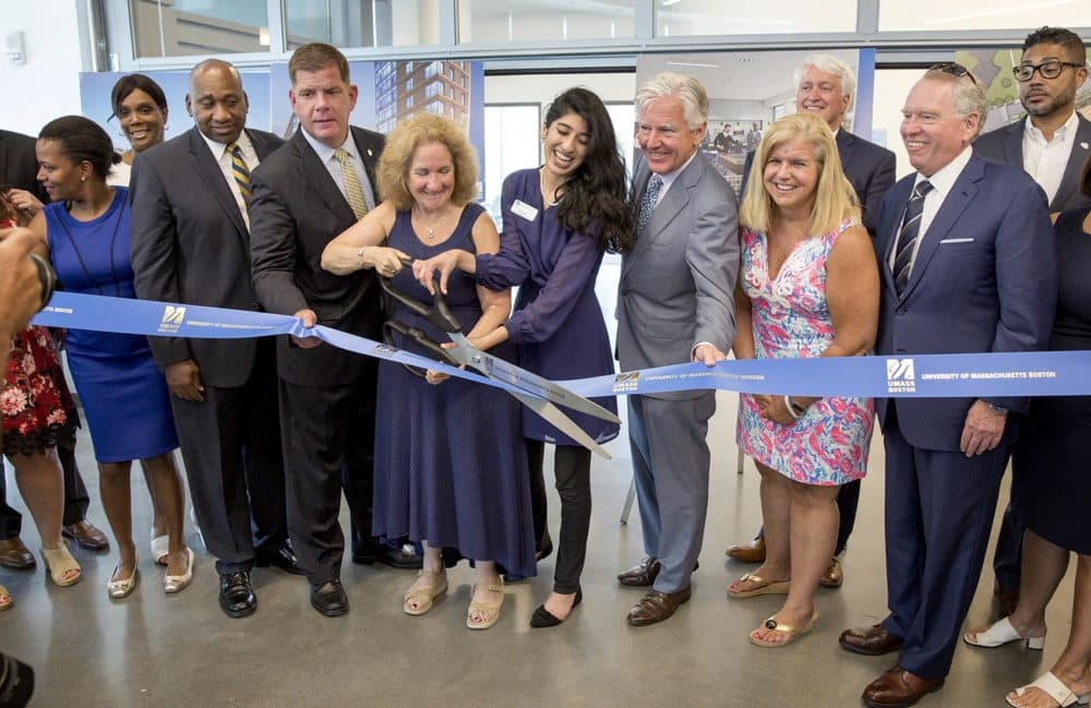 UMass Boston interim chancellor Katherine Newman cuts the ribbon to declare the new UMass dorm open as UMass President Marty Meehan, Boston Mayor Marty Walsh, students, university officials and others look on. (Robin Lubbock/WBUR)