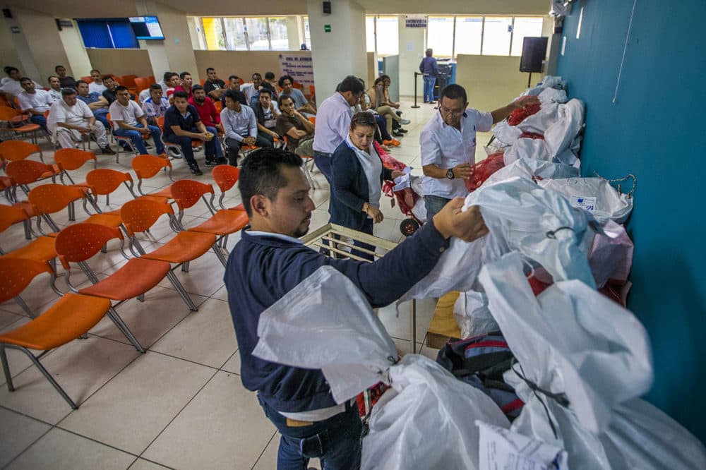 Los oficiales de inmigración llevan bolsas con pertenencias de los deportados salvadoreños a las mesas para devolvérselas a sus legítimos dueños antes de que hagan el trámite y sean liberados. (Jesse Costa/WBUR)
