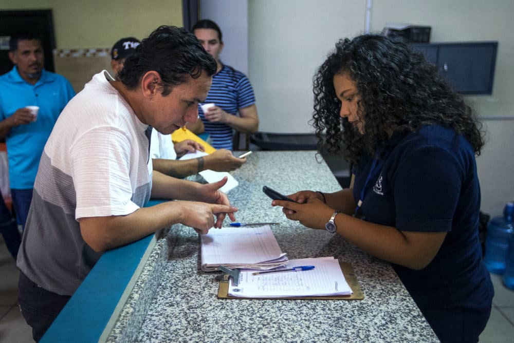 Oficiales de inmigración en La Chacra en San Salvador ayudan a los deportados salvadoreños de los Estados Unidos a comunicarse con su familia y amigos en el área de San Salvador. (Jesse Costa/WBUR)