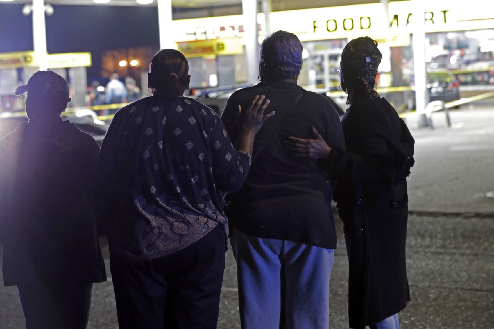 A woman is comforted by others as police investigate the scene of a Mardi Gras day shooting that left at least one dead and others injured, in the lower ninth ward in New Orleans, Tuesday, Feb. 13, 2018. (Gerald Herbert/AP)