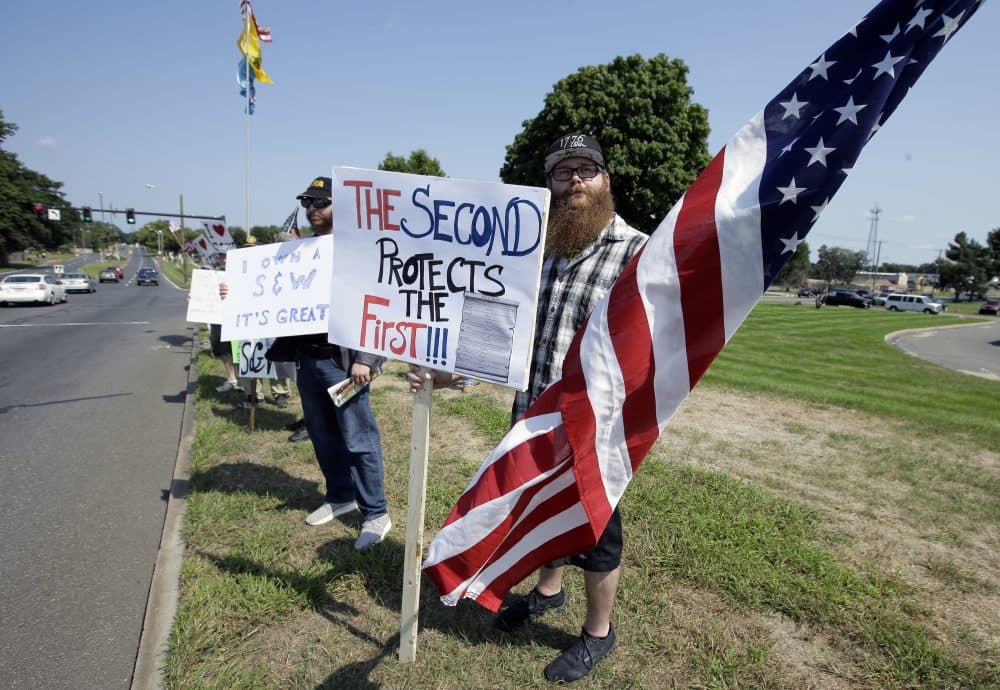 Counter-protester John Allen, of Worcester, center, holds a placard defending Second Amendment rights near the headquarters of gun manufacturer Smith &amp; Wesson on Sunday. (Steven Senne/AP)