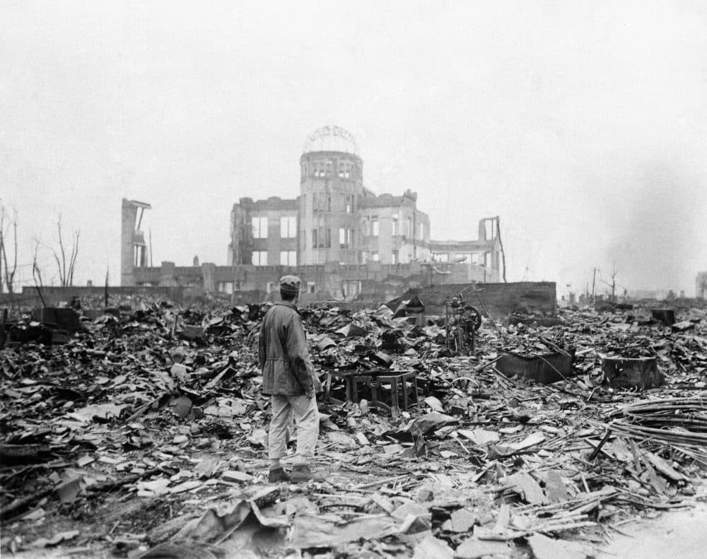 An allied correspondent stands in the rubble in front of the shell of a building that once was a movie theater in Hiroshima, Japan, a month after the first atomic bomb ever used in warfare was dropped by the U.S. on Aug. 6, 1945. (Stanley Troutman/AP)