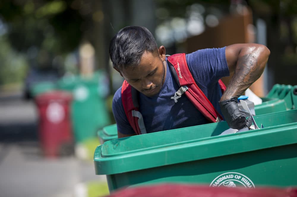 Lowell recycling enforcement coordinator Bora Chhun checks a recycling bin for non-recyclable items on Beacon Street in Lowell. (Jesse Costa/WBUR)