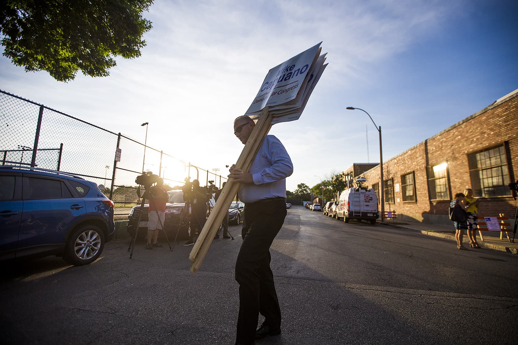 A Michael Capuano supporter crosses the street with a hand full of signs in the early morning on Primary Election Day. (Jesse Costa/WBUR)