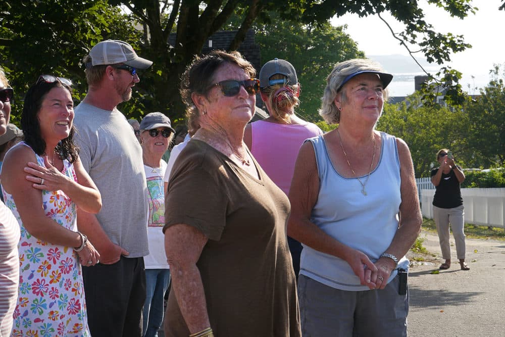 Gwen Lynch's grandmother Anne Schenck (center, in brown) and other Cuttyhunkers look on as two children enter the schoolhouse. (Max Larkin/WBUR)