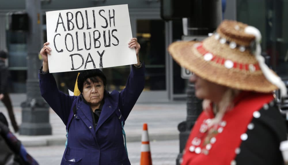 Lovella Black Bear, left, holds a sign calling for the abolishment of Columbus Day during a 2015 demonstration for Indigenous Peoples' Day in Seattle. (Elaine Thompson/AP)