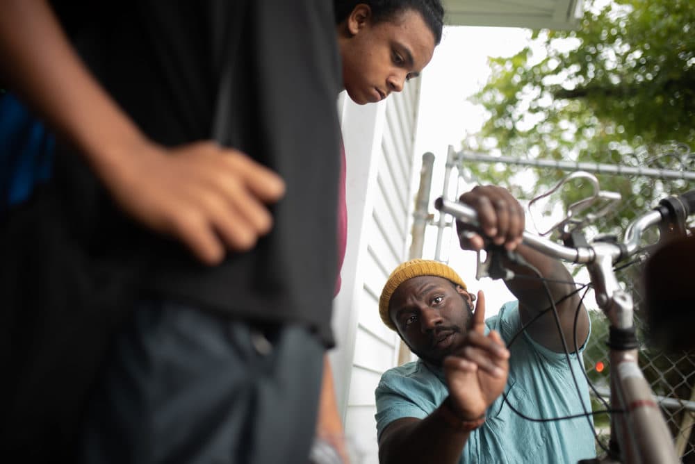 Theon Lee, right, spends time with Dorian Jones, 13, (not pictured) and Jayden Holland, 14, left, teaching them about the brakes on a bicycle at The Biker Boyz &amp; Girlz Shop in Indianapolis. (Lucas Carter for Here &amp; Now)