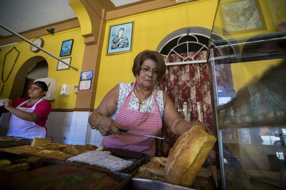 Isabel Quintanilla prepares to slice one of the many breads she offers to customers at her bakery Panaderia Pacita Quintanilla in San Vicente, El Salvador. Her daughter Irma Flores currently lives in Haverhill and is at risk of deportation when her TPS status expires next year. (Jesse Costa/WBUR)