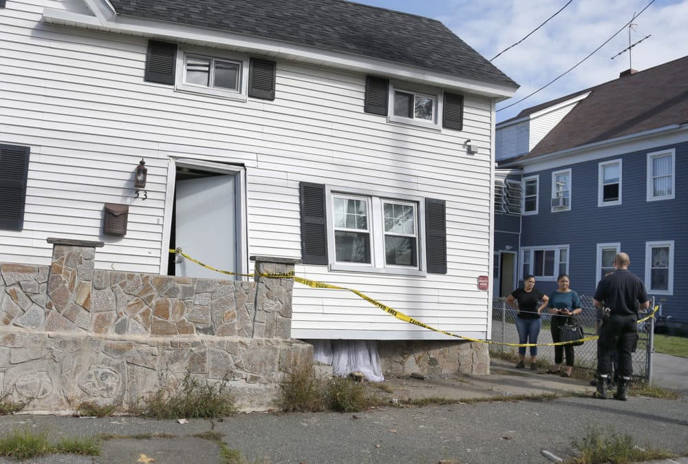 Fire inspectors talk to the residents of a home that was blown off its foundation on Kingston Street in Lawrence. (Mary Schwalm/AP)