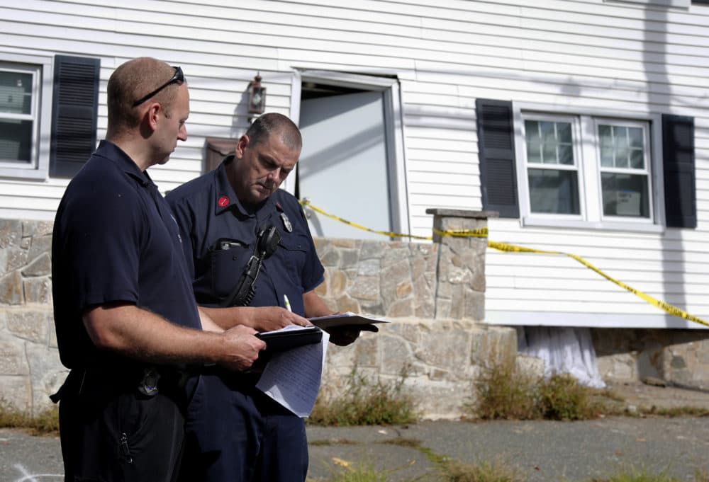 Fire inspectors take notes outside a house that was blown off its foundation on Kingston Street in Lawrence. (Mary Schwalm/AP)