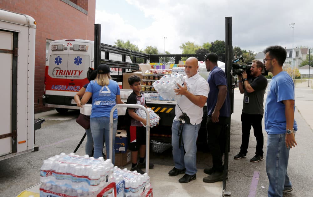 Volunteers help to unload a truck of donations outside the Parthum School in Lawrence Friday. (Mary Schwalm/AP)