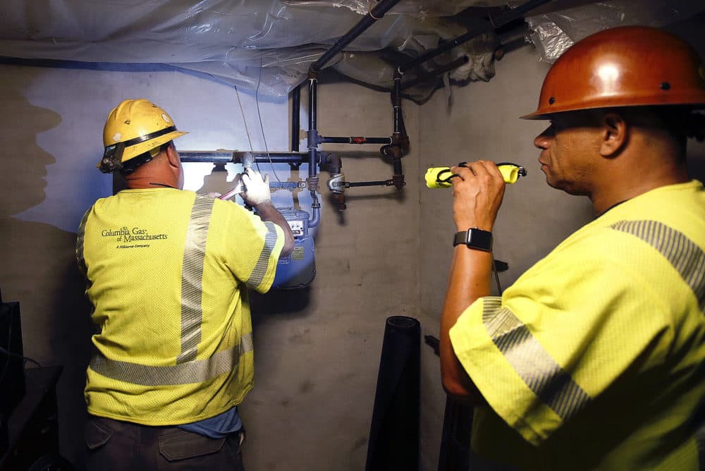 Columbia Gas employee Brian Jones shines a flashlight so his partner, using a wrench, can shut off the gas in a home Friday in Andover. (Winslow Townson/AP)