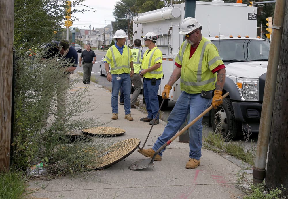 A worker with Columbia Gas pries the manhole cover open as they work to make sure there are no gas leaks at the corner of Parker and Salem streets in Lawrence. (Mary Schwalm/AP)