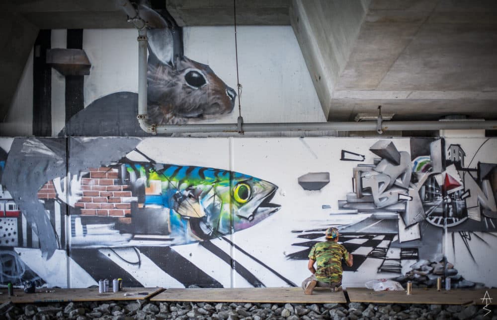 Percy Fortini-Wright paints his mural under the overpass. (Courtesy Adam Straughn)