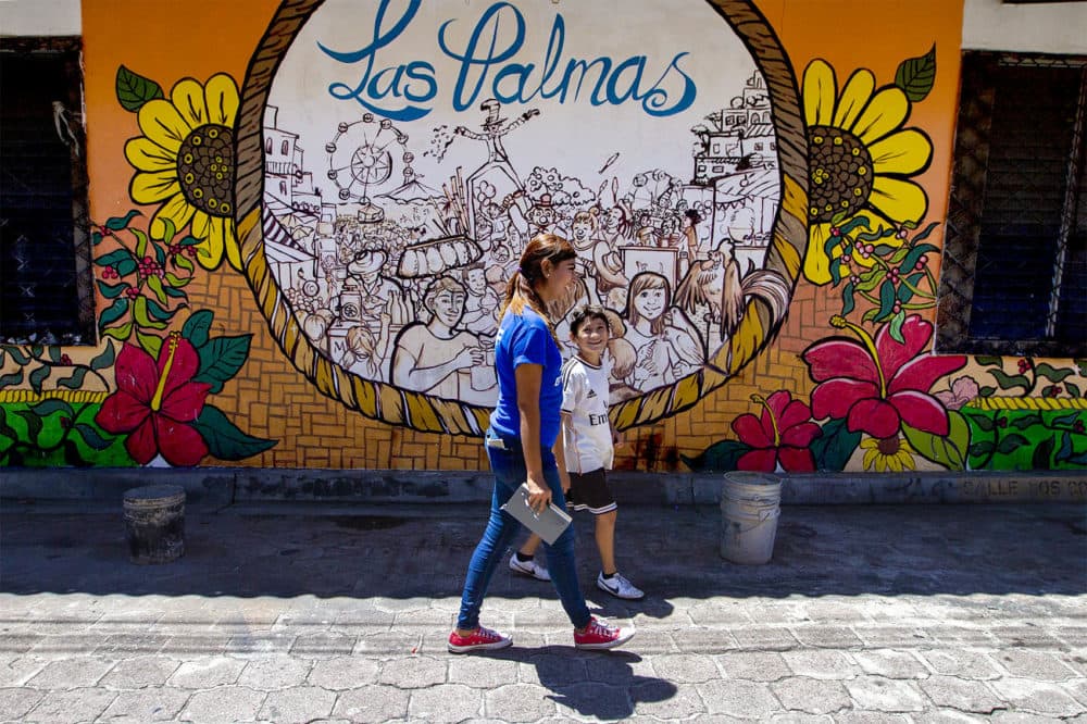 A Glasswing International staff member walks through town with a young boy who lives in Las Palmas. (Jesse Costa/WBUR)
