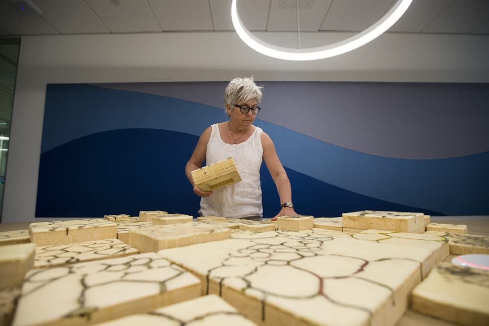 Jodi Colella sets up blocks on a conference room table to prepare her piece to be displayed on the 10th floor in the Boston Consulting Group's building in the Seaport. (Jesse Costa/WBUR)