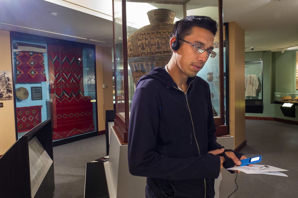 Archaeology Ph.D. student Wade Campbell, of the Navajo Nation, listens to the Native American Poets Playlist at the Peabody Museum. (Andrea Shea/WBUR)