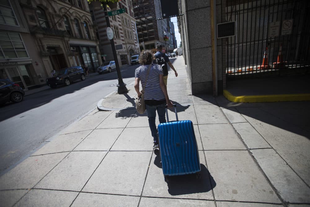 Nancy, who came to Boston for shelter and services after becoming homeless in November, pulls her belongings in a suitcase outside St. Francis House in July. (Jesse Costa/WBUR)