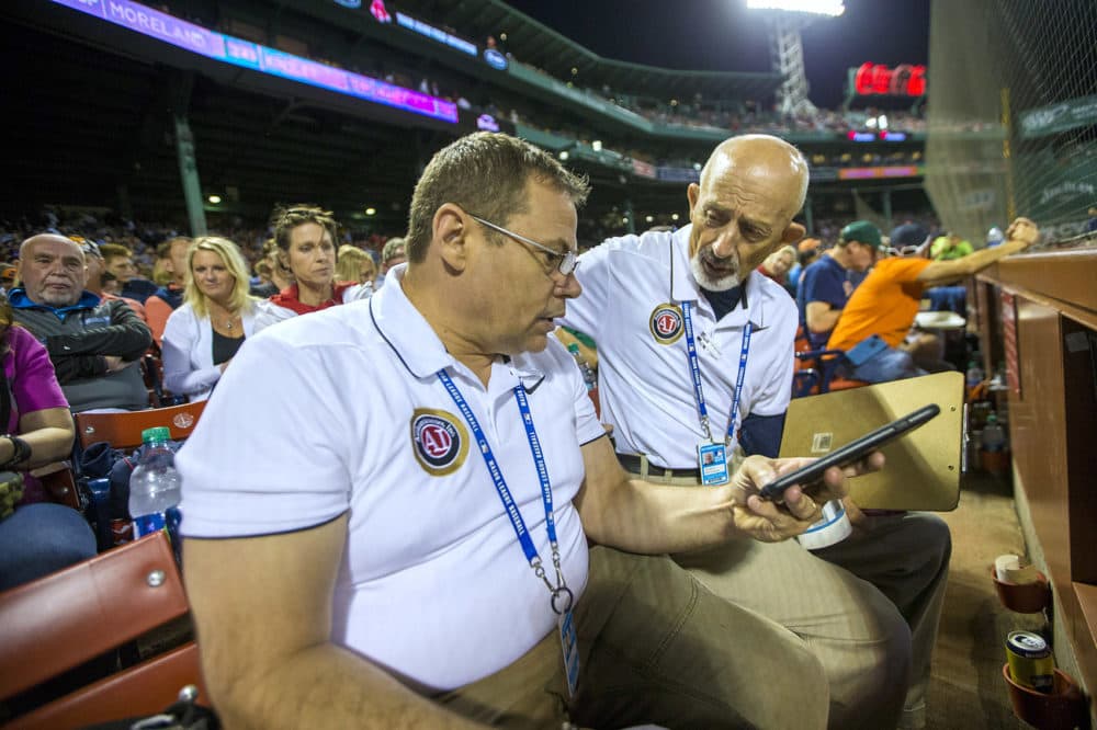 Juan Seoane, left, and John Martino of Authenticators Inc. prepare to watch a Red Sox-Astros game and take notice of prospective items that may become memorabilia. (Jesse Costa/WBUR)