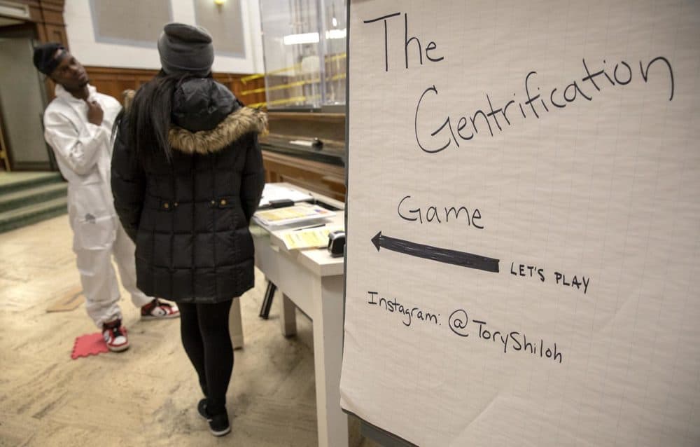 Artist Tory Bullock invites a contestant to play &quot;The Gentrification Game.&quot; (Robin Lubbock/WBUR)
