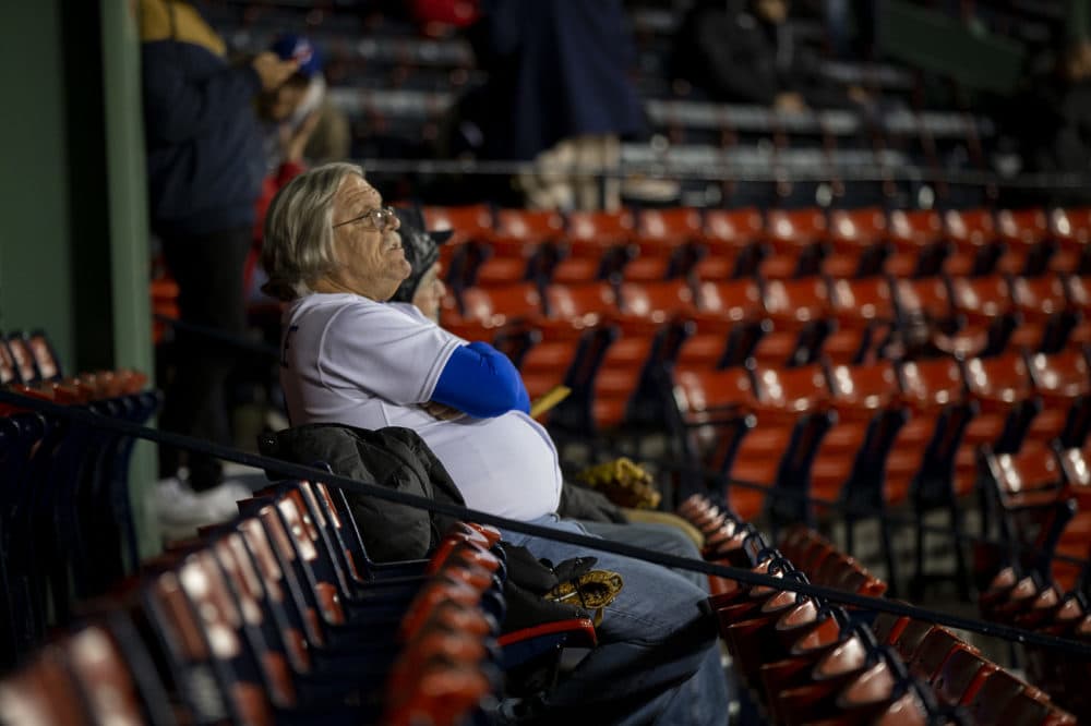 A Los Angeles Dodgers fan watches as the rain begins falling on Fenway Park prior to the start of the first World Series game between the Red Sox and Dodgers. (Jesse Costa/WBUR)