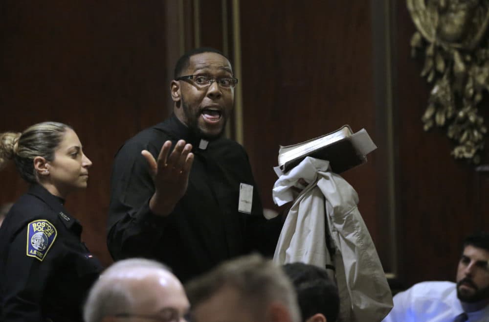 Rev. Darrell Hamilton, right, a pastor at First Baptist Church, in Boston, is escorted away by a Boston police officer, left, after interrupting remarks by Attorney General Jeff Sessions. (Steven Senne/AP)