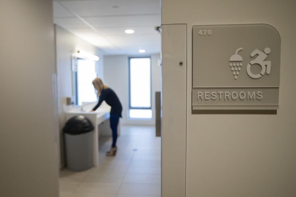 Chloe Strange, who supervises RAs in UMass Boston's new dorm, uses a wash basin in an open concept, all-inclusive bathroom. The bathroom features private rooms with showers and toilets. (Jesse Costa/WBUR)