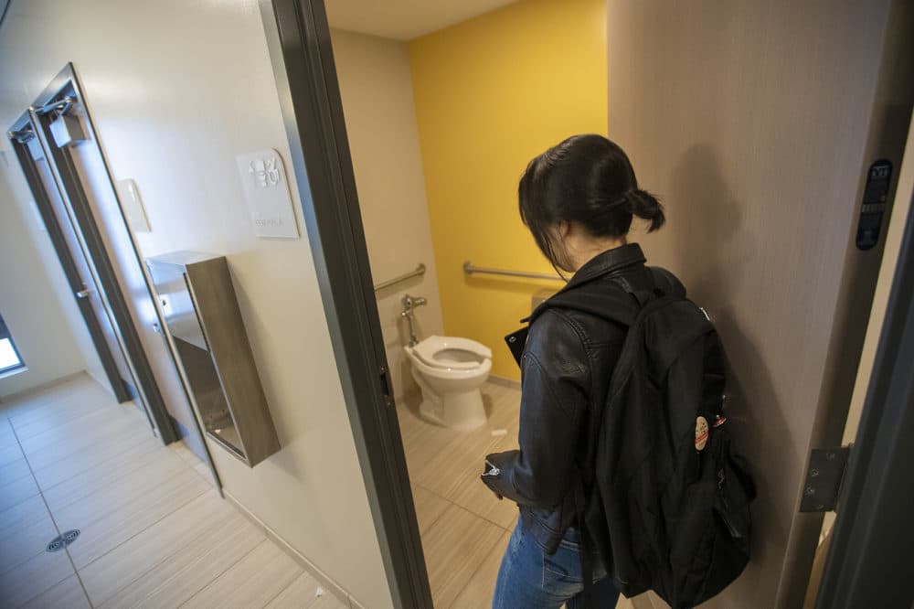 UMass Boston student Chanel An enters one of the toilet and shower rooms in the bathroom at the new dorm. (Jesse Costa/WBUR)