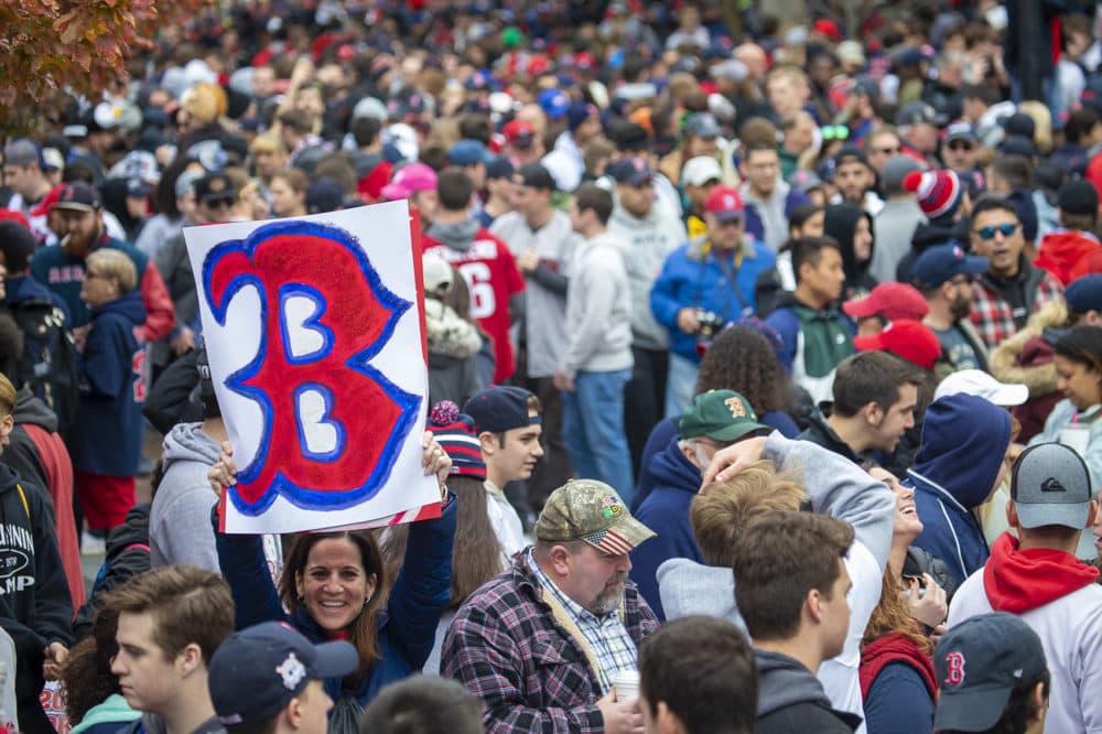 A woman holds up a giant B sign in the middle of the crowd. (Jesse Costa/WBUR)