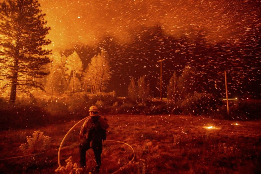 Embers fly above a firefighter as he works to control a backfire as the Delta Fire burns in the Shasta-Trinity National Forest, Calif., on Thursday, Sept. 6, 2018. The blaze had tripled in size overnight. (Noah Berger/AP)