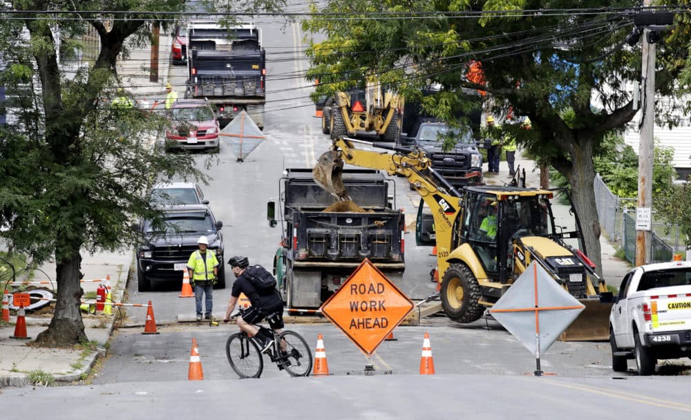 A bicyclist takes a turn at a road block as utility contractors dig up the road above natural gas lines along Brookfield Street in Lawrence on Sept. 20. (Charles Krupa/AP)