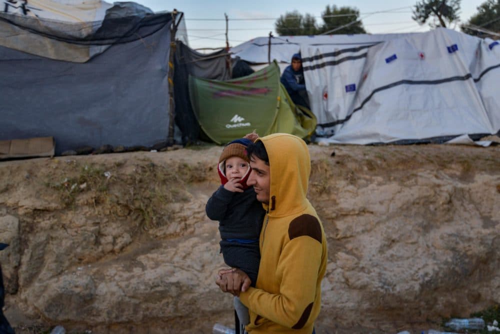 A man carries a child in a camp outside the refugee camp of Moria, in the northern Greek island of Lesbos on September 25, 2018. (Aris Messinis/AFP/Getty Images)