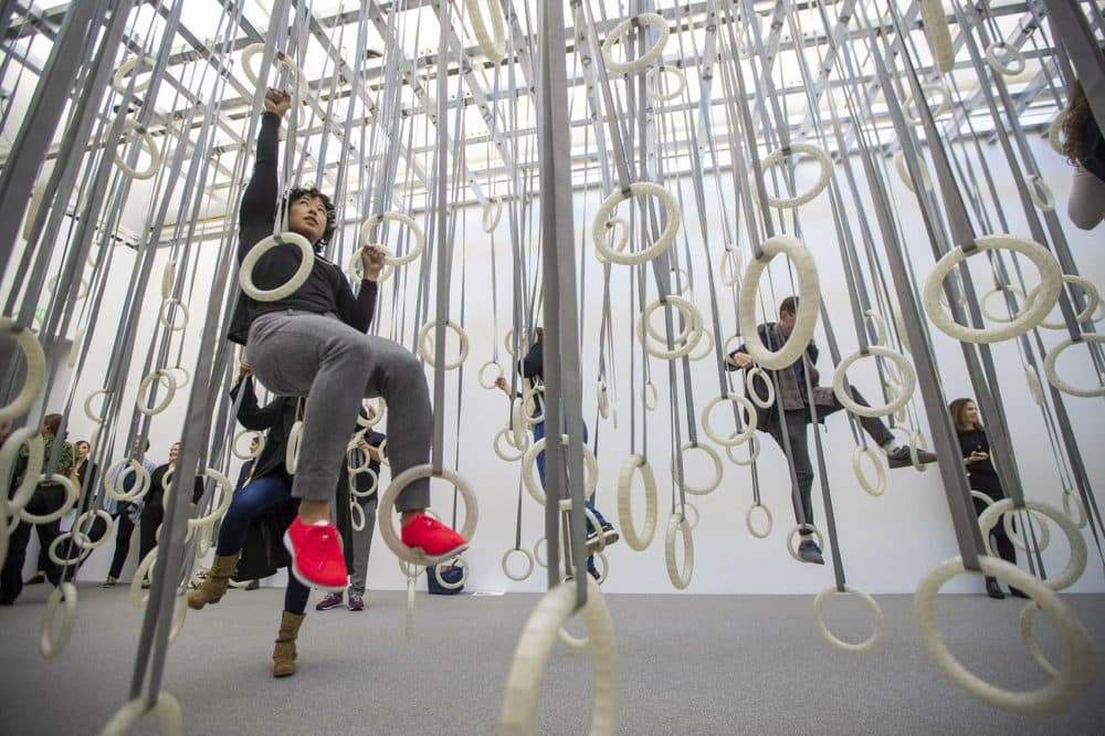 ICA curator Ellen Tani climbs through the rings of &quot;In The Fact of Matter.&quot; (Jesse Costa/WBUR)