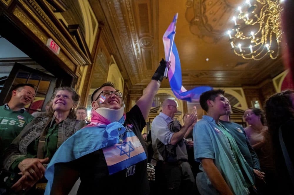 Mateo Cox waves a transgender flag excitedly as the room at the Fairmont Copley learns of the election day win. (Jesse Costa/WBUR)