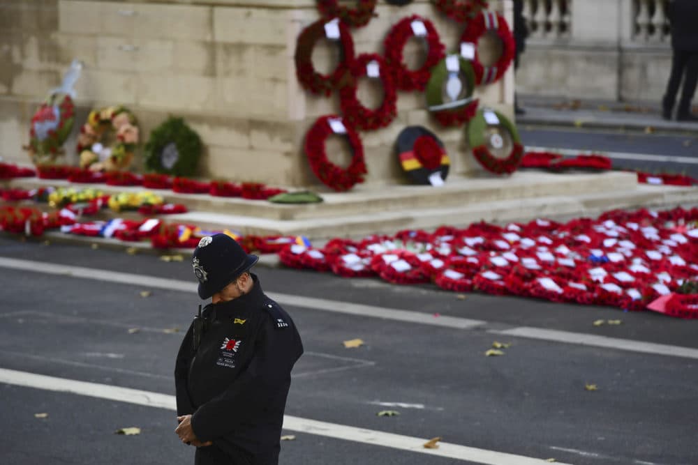 A policeman bows his head with wreaths laid at the Cenotaph during the remembrance service in Whitehall, central London, Sunday Nov. 11, 2018. The ceremony marks the 100th anniversary of the signing of the Armistice which ended the First World War. (Victoria Jones/Pool via AP)
