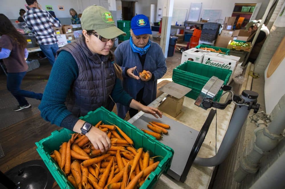 Daniela Marzuca, left, and Dalia Rosas of Whitemars Farm in Dracut weigh one-pound bags of carrots at the New Entry Sustainable Farming Project in Lowell. (Jesse Costa/WBUR)