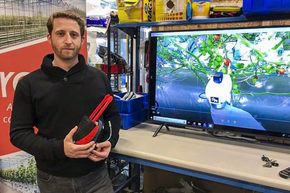 Co-founder and CEO of Root AI Joshua Lessing holds his robot’s gripper. (Andrea Shea/WBUR)