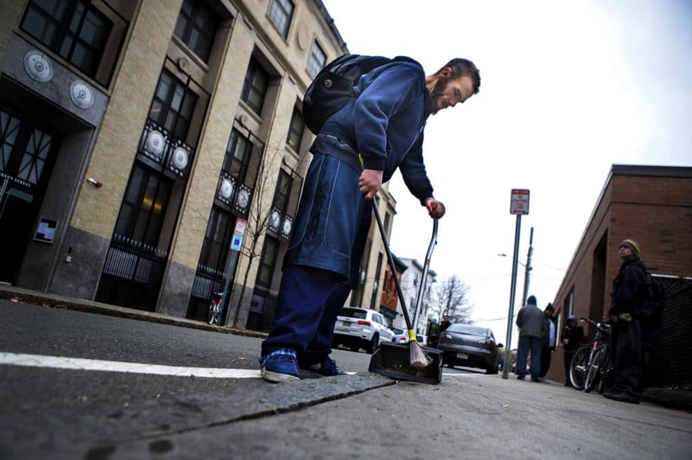 Michael sweeps up cigarettes and other debris from the sidewalk outside a needle exchange in Cambridge. (Jesse Costa/WBUR)