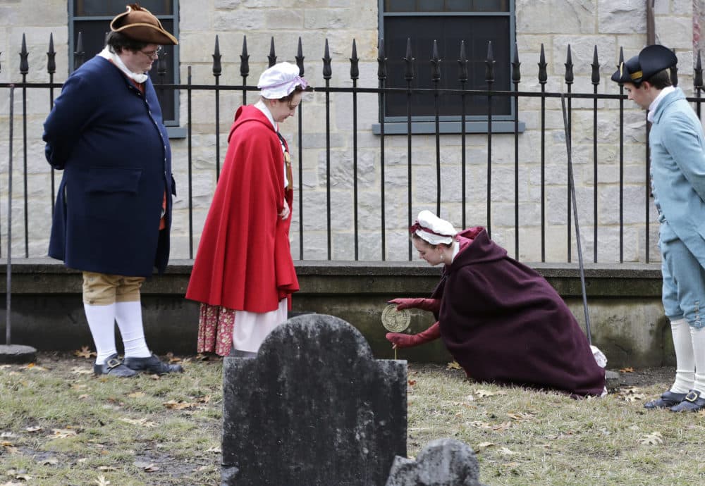Actor-interpreters from the Boston Tea Party Ships and Museum, from left, Tim Lawton, Jillian Couillard, Sierra Grabowska and Stephen Chueka, place commemorative markers at Central Burying Ground on Boston Common. (Elise Amendola/AP)