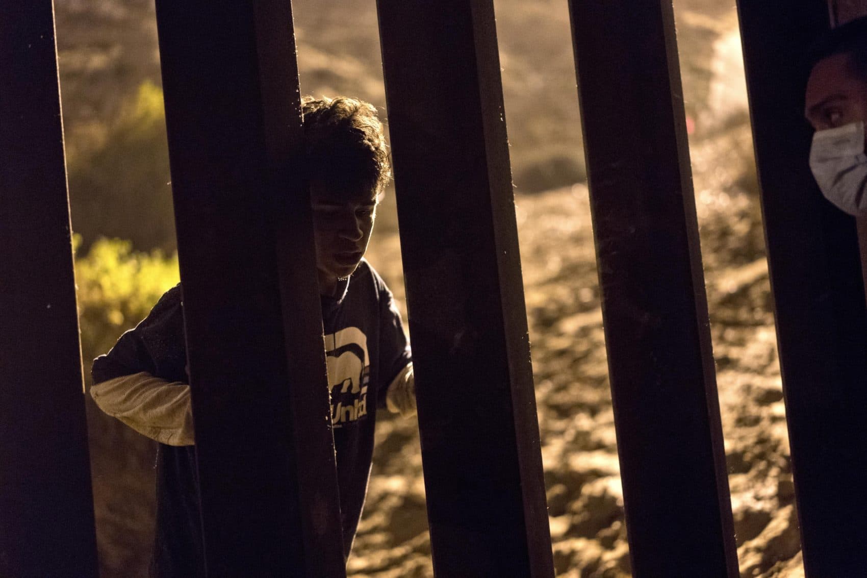 Salvadoran migrant Cesar Jobet, left, talks with fellow migrant Daniel Jeremias Cruz, from the U.S. side of the in Playas de Tijuana, Mexico on Nov. 30. (Ramon Espinosa/AP)
