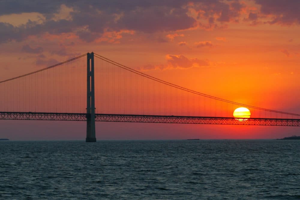 The sun sets over the Mackinac Bridge and the Mackinac Straits as seen from Lake Huron. The bridge is the dividing line between Lake Michigan to the west and Lake Huron to the east. (AP Photo/Al Goldis)