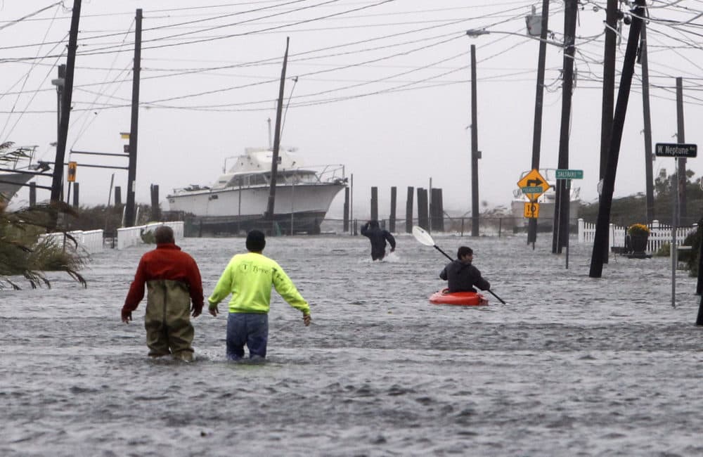 People wade and paddle down a flooded street as Storm Sandy approaches on Oct. 29, 2012, in Lindenhurst, N.Y. (Jason DeCrow/AP)